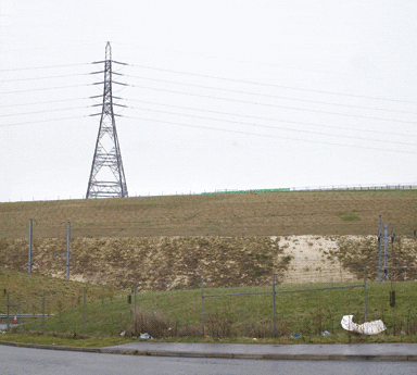 The site of the monument is marked by the green fence; the cutting in the foreground carries the Channel Tunnel rail link